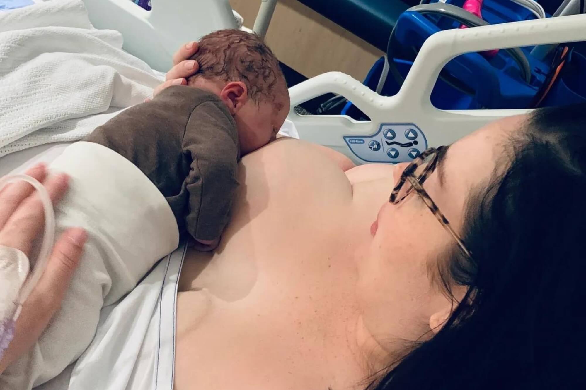 Mother in a hospital bed initiating breastfeeding with her baby after a c-section